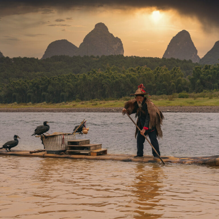 Eighty year old chinese fisherman on boat at sunset in yangshuo, china